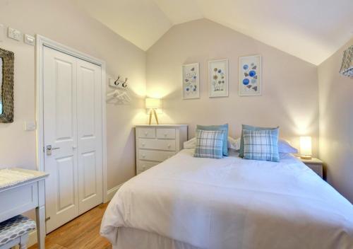 a bedroom with a large white bed with blue pillows at Tui Cottage in Snape