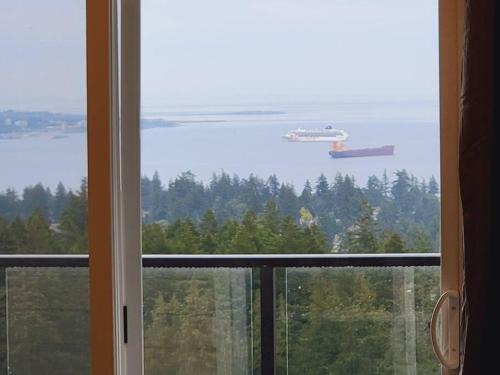 a window with a view of the water and a ship at Eagle's View Penthouse in Victoria