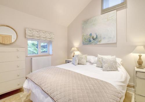 a white bedroom with a bed and a dresser at Kakapo Lodge in Snape