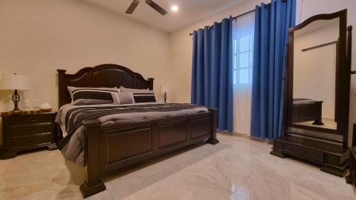 a bedroom with a bed with blue curtains and a mirror at Palacio Huatulco - 2D in Santa Maria Huatulco