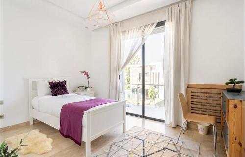 a white bedroom with a bed and a window at Villa Eden luxe in Bouskoura