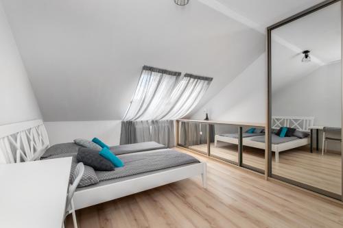 a white room with a bed and a mirror at Tjiraso Apartment in Gdańsk
