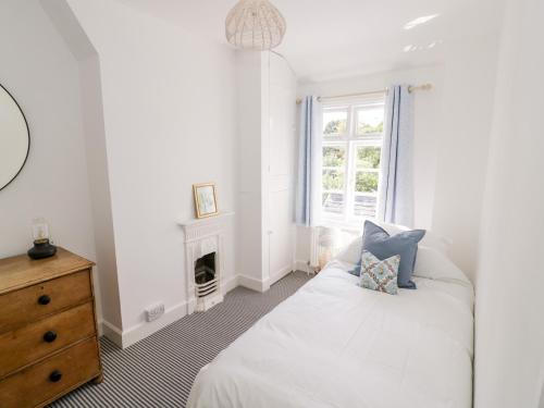 a white bedroom with a bed and a window at Ross Cottage in Evesham