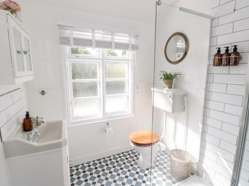 a bathroom with a toilet and a sink and a window at Ross Cottage in Evesham