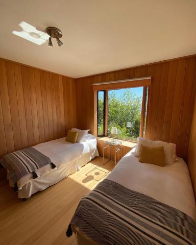 two beds in a room with a window at Cabañas Bahia Celeste, Puerto Varas in Puerto Varas