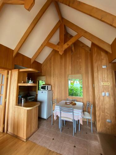 a kitchen and dining room with a table and a refrigerator at Cabañas Bahia Celeste, Puerto Varas in Puerto Varas
