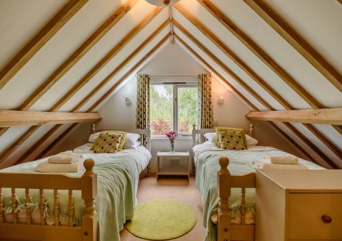 a attic room with two beds and a window at Dragonfly in Rumburgh