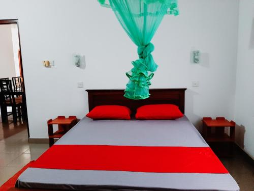 a bedroom with a bed with red pillows and a blue curtain at Marette Holiday Bungalow in Moratuwa