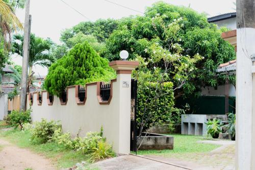 a building with a fence with trees behind it at Marette Holiday Bungalow in Moratuwa