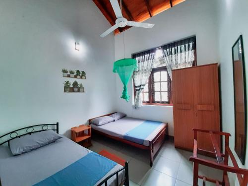 a bedroom with two beds and a ceiling fan at Marette Holiday Bungalow in Moratuwa