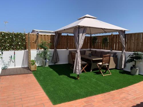 a patio with a table and an umbrella on grass at Apartamento Sotavento Chipiona in Chipiona
