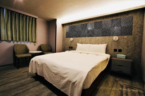 pokój hotelowy z dużym łóżkiem i 2 krzesłami w obiekcie Golden Home Hotel w Tajpej