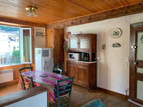 une cuisine avec une table avec des chaises et un réfrigérateur dans l'établissement Joli appartement dans une maison ancienne, à Ax-les-Thermes