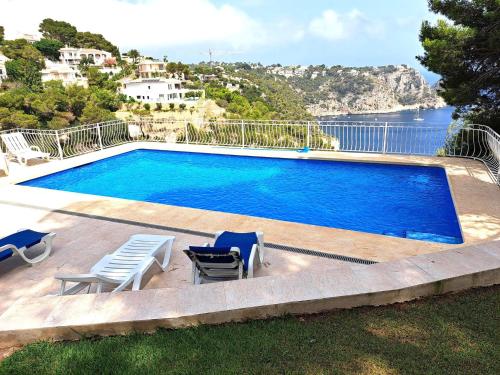a swimming pool with chairs and a view of the water at Holiday Home Maria in Jávea