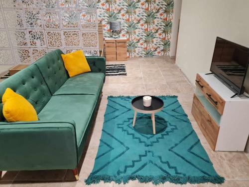 sala de estar con sofá verde y mesa en Chez Karine - Appartement, en Lédenon