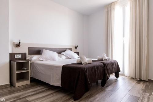 a white bedroom with a bed with two towels on it at Mesón Hostal La Cabaña in Medellín