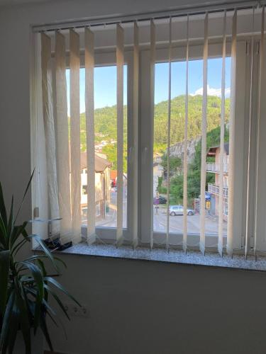 a window with white curtains with a view of a street at Gatto in Jajce