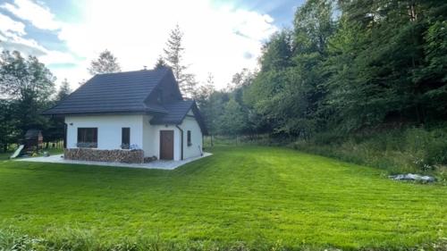 a small white house in a field of green grass at Bórówka in Ujsoły