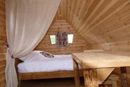 ein Schlafzimmer mit einem Bett in einem Blockhaus in der Unterkunft Les Cabanes Flottantes in Givrauval