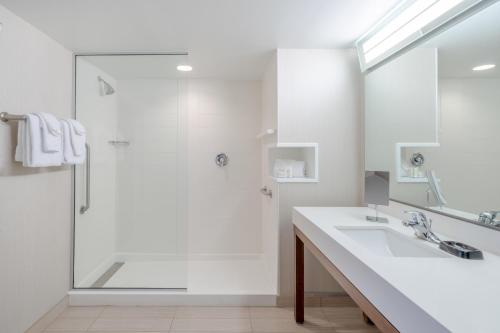 baño blanco con ducha y lavamanos en Courtyard by Marriott Wilkes-Barre Arena, en Wilkes-Barre