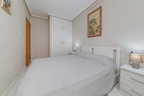a white bedroom with a bed and two night stands at Apartamento Fragata in Torrevieja