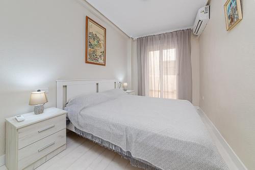 ein weißes Schlafzimmer mit einem Bett und einem Fenster in der Unterkunft Apartamento Fragata in Torrevieja