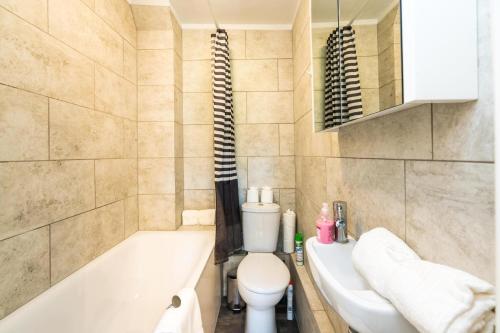 La salle de bains est pourvue d'une baignoire, de toilettes et d'un lavabo. dans l'établissement Super 1BD Flat minutes from Kings Cross Station, à Londres