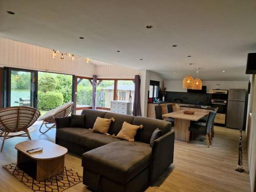 ein Wohnzimmer mit einem Sofa und einem Tisch sowie eine Küche in der Unterkunft Chalet moderne au bord d'un lac in Saint-Sauveur-lès-Bray