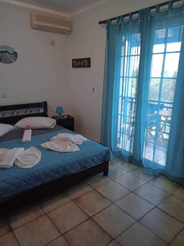 a bedroom with a bed with blue curtains and windows at The Captain in Elafonisos