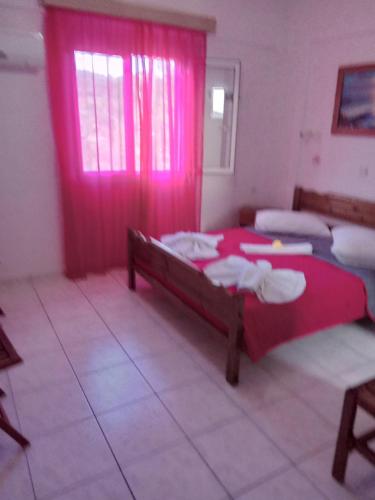 a bedroom with two beds and a window with pink curtains at The Captain in Elafonisos