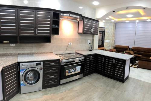 a kitchen with a stove and a washer and dryer at The Pine Tree Chalet in Jerash