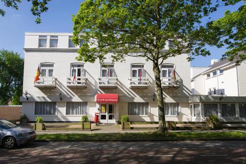 a white building with a tree in front of it at Bed & Breakfast Van Marion in Oostvoorne
