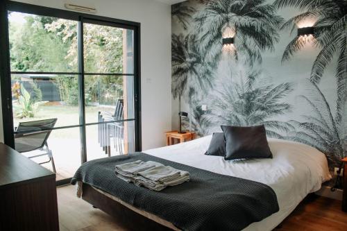 ein Schlafzimmer mit einem Bett mit einem Palmenmilch an der Wand in der Unterkunft Les cabanes de l'océan, Villa confort proche plage sauvage in Messanges