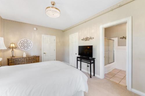 a white bedroom with a bed and a television at Presidents House B & B in Plainview