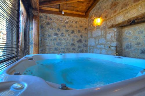 Cozy Villa near Mount Parnassos في أراخوفا: حوض استحمام كبير في غرفة بجدار حجري