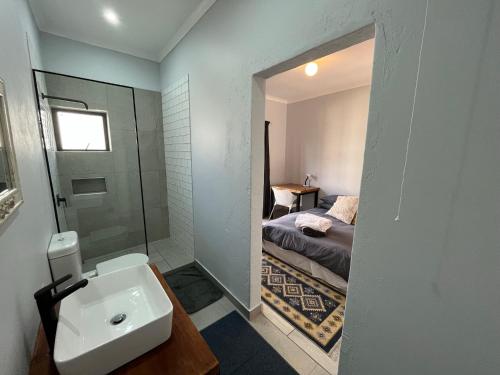 a bathroom with a sink and a bedroom with a bed at Casa Bravo - Cozy Traveller in Pretoria