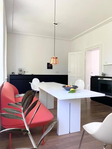 a dining room with a white table and red chairs at Zehuus mit Domblick und Dachterrasse in Cologne