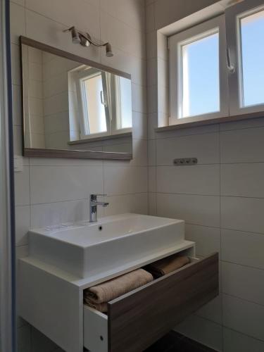 a bathroom with a white sink and two mirrors at Apartmani Zen in Sumartin