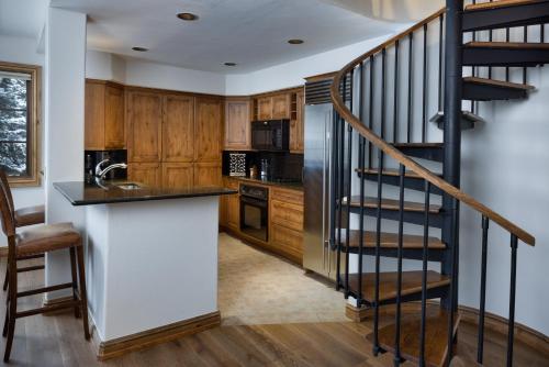 a kitchen with wooden cabinets and a spiral staircase at Gravity Haus Vail in Vail