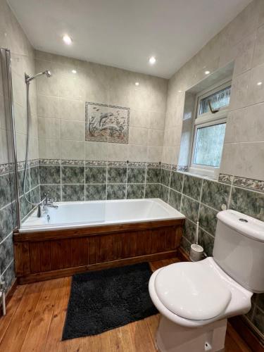 a bathroom with a bath tub and a toilet at Cosy Single Room for ONE person in Bromley