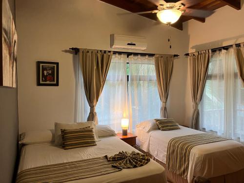 two beds in a room with a window at Villa Tortuga in Nosara