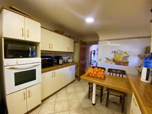 a kitchen with white cabinets and a table with oranges on it at Parcela Olmué La Luz in Olmué