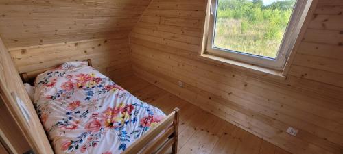 a bedroom with a bed in a wooden room with a window at Drewniak in Wisełka