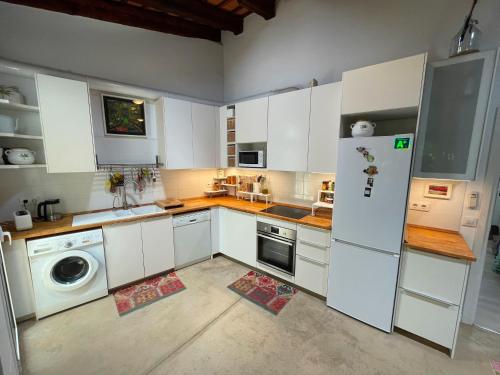 cocina con armarios blancos y nevera blanca en Casa amb jardí a Castell d'Aro, en Castillo de Aro
