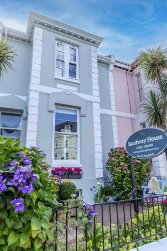 a white house with a sign in front of it at Sandway House in Torquay