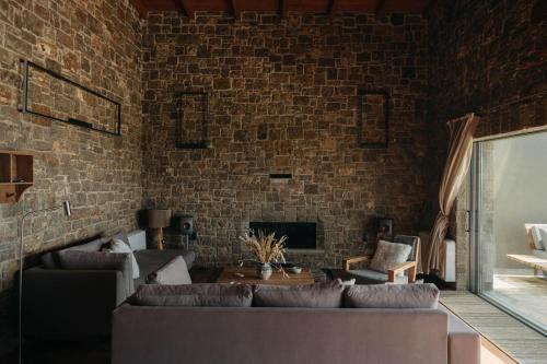 a living room with a couch and a brick wall at Real Life Homes luxurious seafront villas each with their own private pools in Korakokhórion