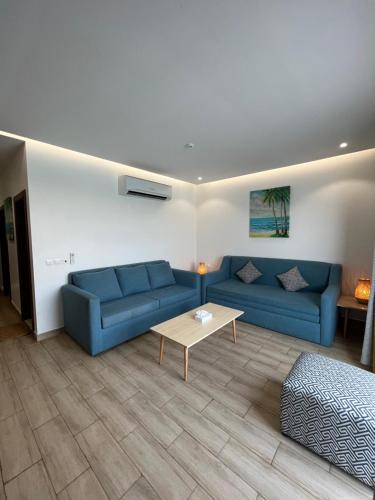 ein Wohnzimmer mit blauen Sofas und einem Tisch in der Unterkunft غرفة صالة بلكونة على الشاطئ - عوائل in Durrat Al-Arus