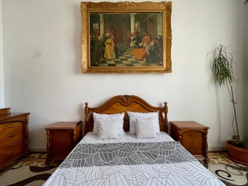 a bedroom with a bed with a painting on the wall at M & I Apartment 1 in Târgu-Mureş