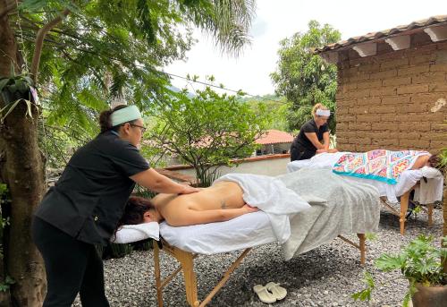 une femme recevant un massage d'un homme sur un lit dans l'établissement Hospedaje Casa Teotleco, à Tepoztlán