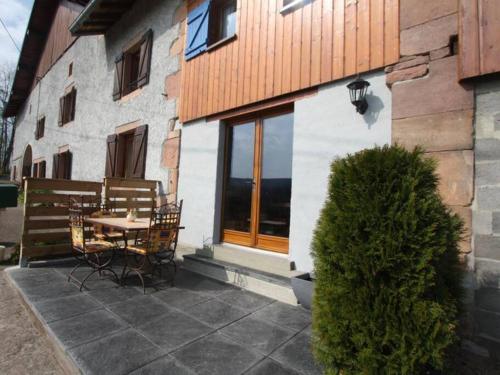 a patio with a table and chairs next to a building at LE POINT DU JOUR 88460 DOCELLES in Docelles